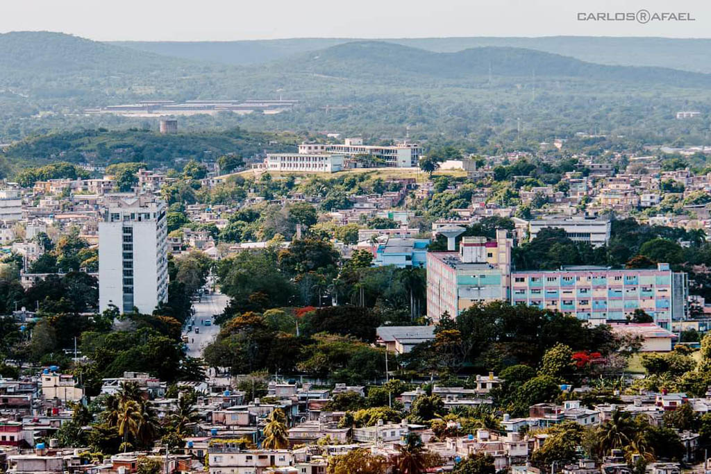 Fotografía tomada desde la Loma de la Cruz, desde donde sin visibles el Edificio 12 plantas, que es sede en su cima del Restaurante El Polinesio; contiguo a esta estructura, el Hospital Lenin. También se aprecia la escuela conocida como La Fornet (otrora Los Maristas). Loma de la Cruz 9